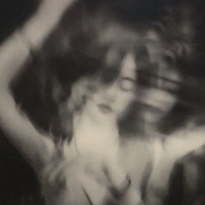 a blurry photo of a woman with her arms behind her head and hands in the air