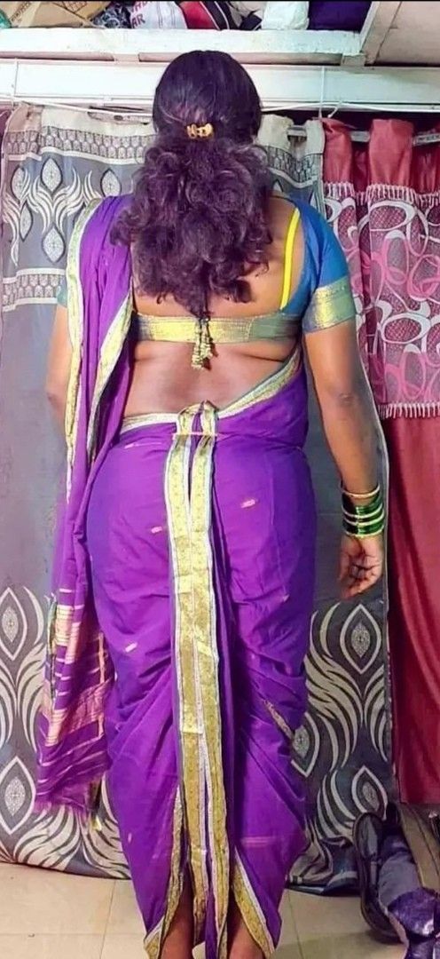 a woman in a purple sari standing next to a wall