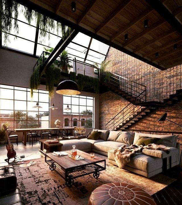 a living room filled with furniture next to a brick wall covered in plants and windows