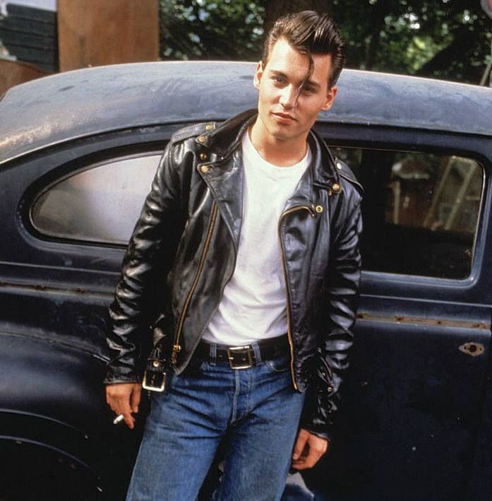 a man standing next to an old car wearing a black leather jacket and white t - shirt