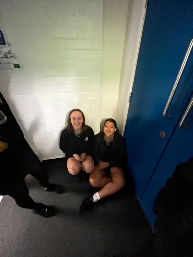 three women sitting on the floor next to a door with a dog in front of them