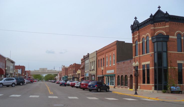 cars are parked on the side of an empty street in front of brick buildings with arched windows