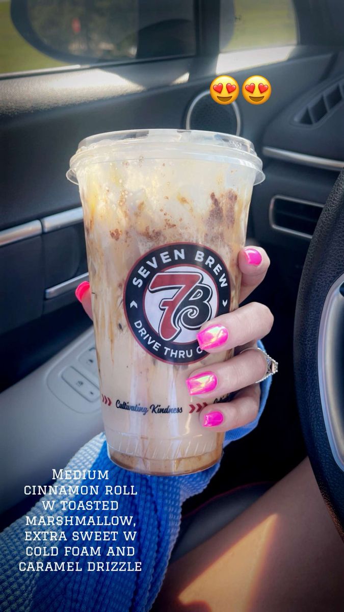 a woman holding up a cup of coffee in her hand with the words seven elevens on it