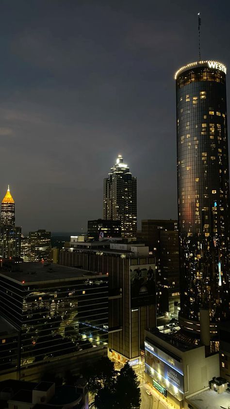 the city skyline is lit up at night, with skyscrapers in the foreground