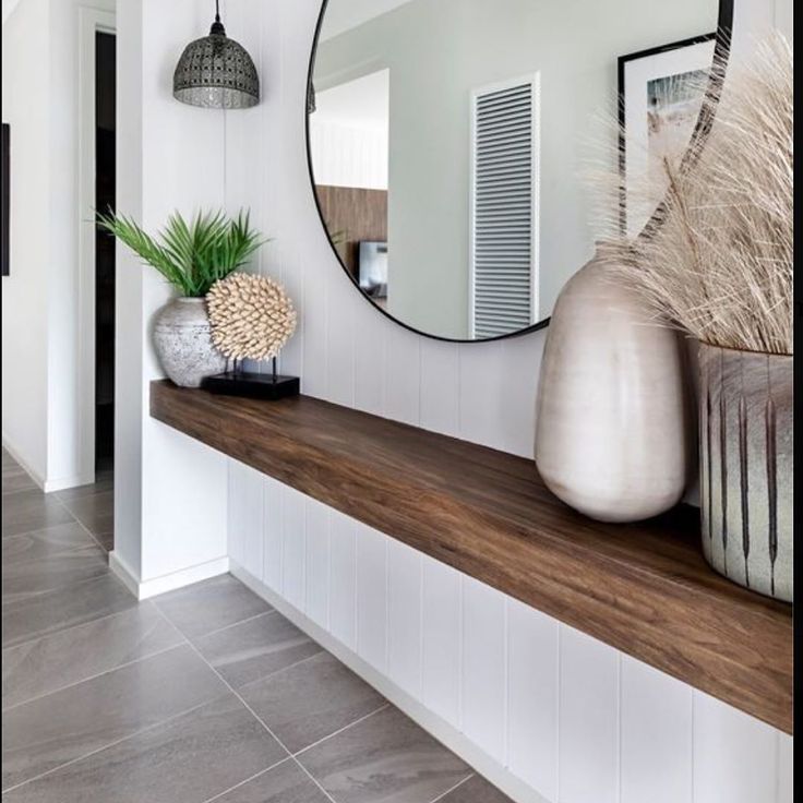 there is a mirror and vases on the shelf in this room with tile flooring