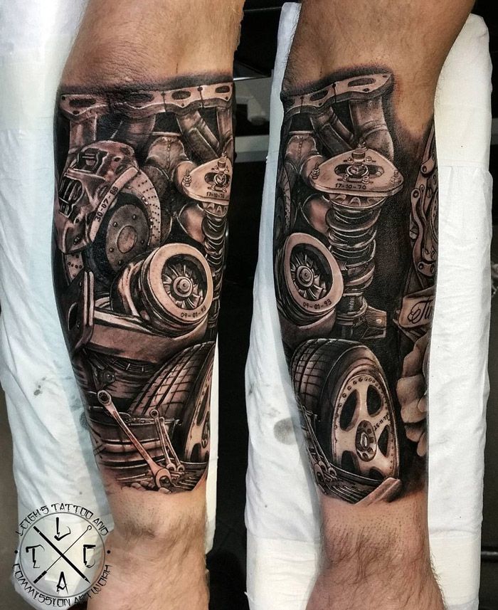 two men with tattoos on their legs and one has a car engine in the background