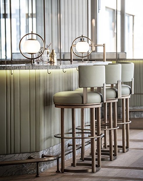 a row of bar stools in front of a counter with two lamps on it