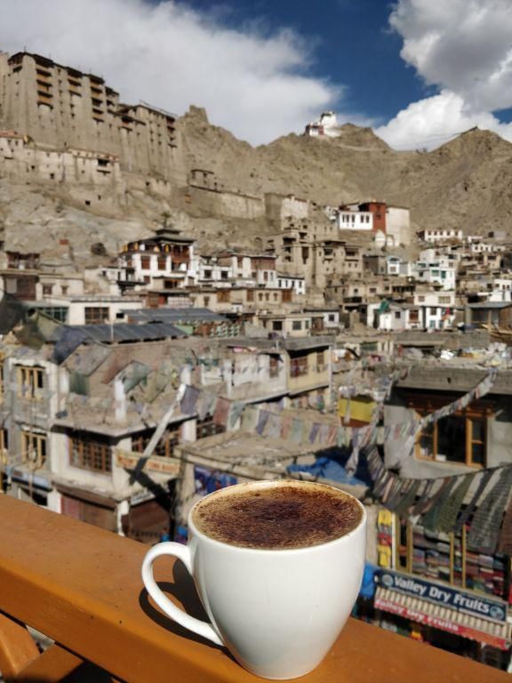 a cup of coffee sitting on top of a wooden table next to a cityscape