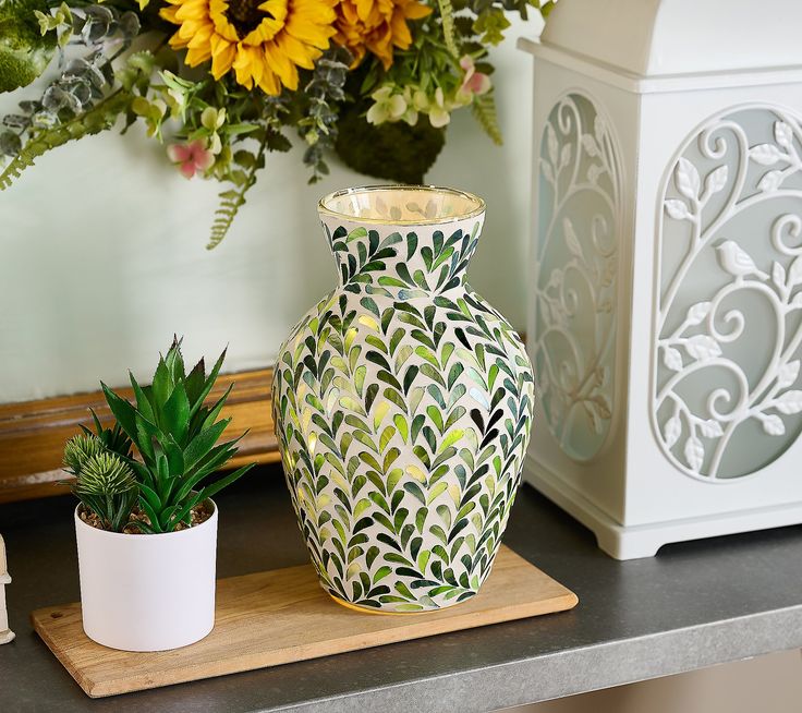 a vase sitting on top of a wooden table next to a potted plant and other decorations