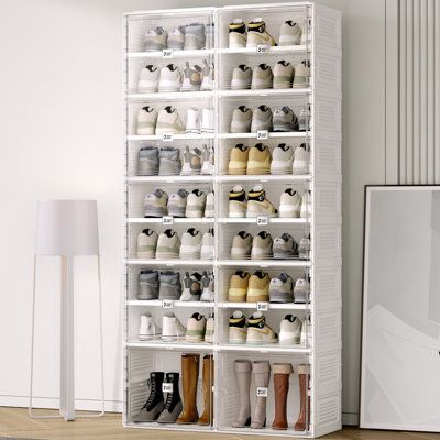 a white shelf filled with lots of pairs of shoes next to a lamp on top of a hard wood floor