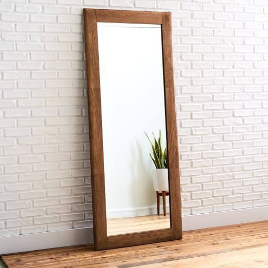 a large mirror sitting on top of a wooden floor next to a potted plant