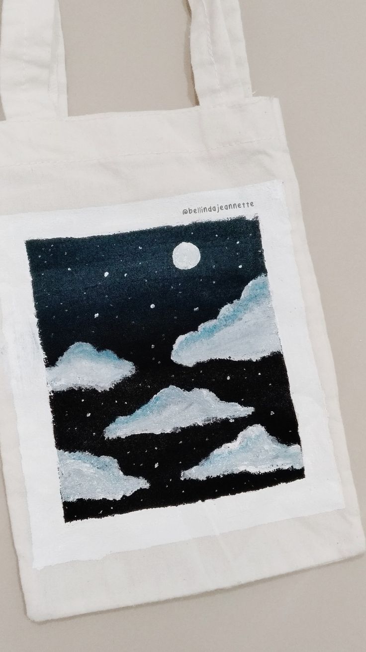 a white bag with an image of the sky and clouds painted on it's side