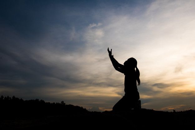 a silhouette of a person reaching up to the sky