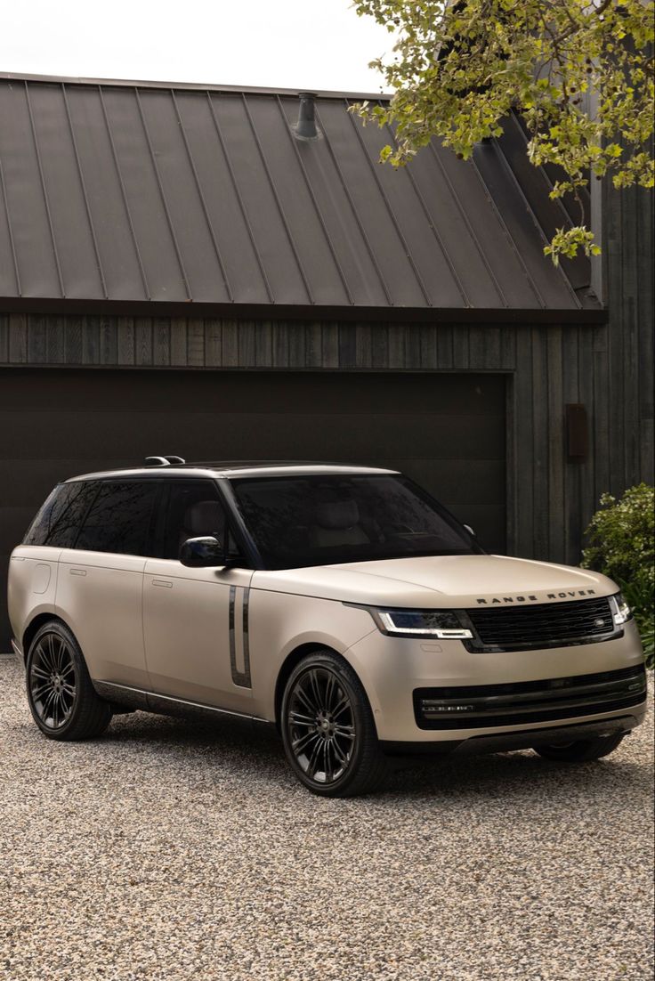 a white range rover parked in front of a garage