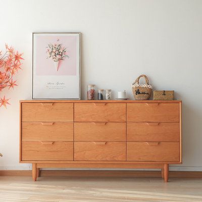 a wooden dresser sitting next to a potted plant on top of a hard wood floor