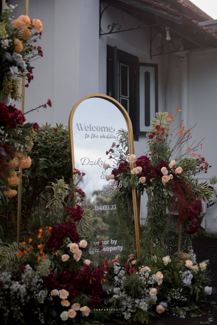 a welcome sign surrounded by flowers in front of a building