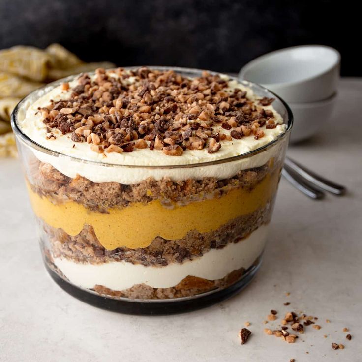 an image of a dessert in a glass bowl on a table with crackers and spoons