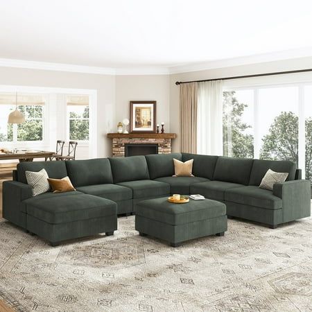 a living room with a large sectional couch and ottoman in front of a fire place