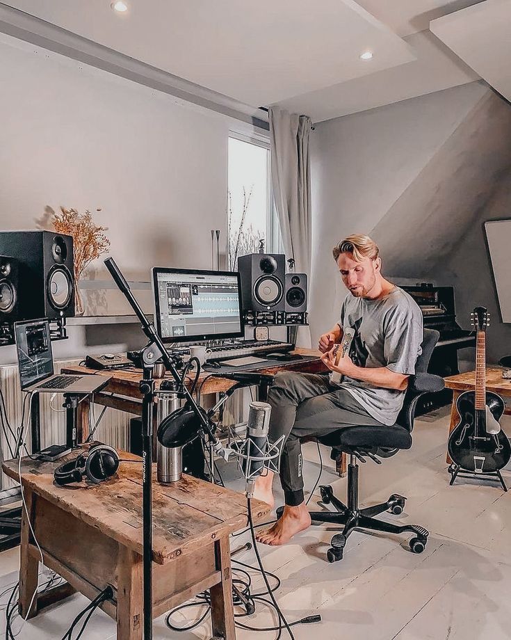 a man sitting in front of a desk with musical equipment