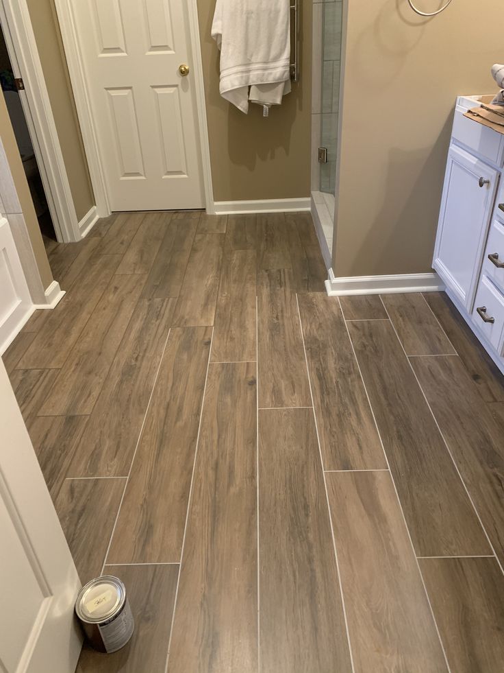 a bathroom with wood look tile flooring and white cabinets in the shower stall area