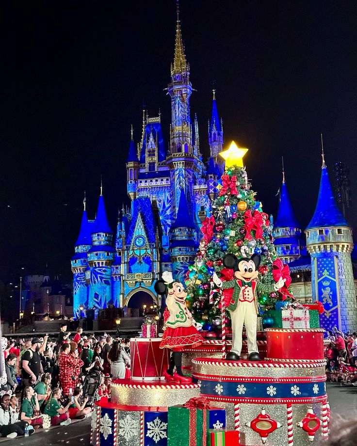 the mickey mouse float is decorated with christmas lights and decorations at night in front of disney's castle