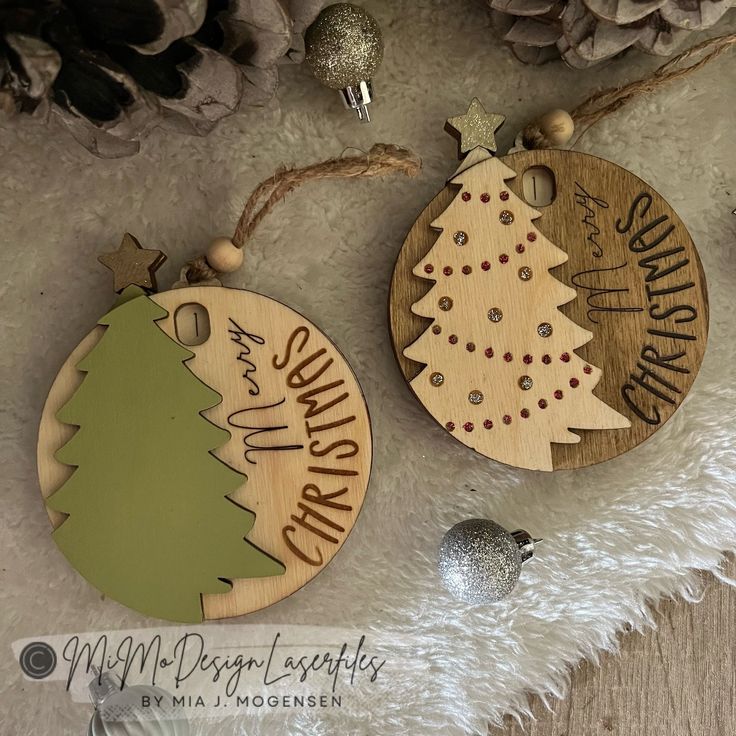 two wooden christmas ornament hanging on a white furnishing next to pine cones