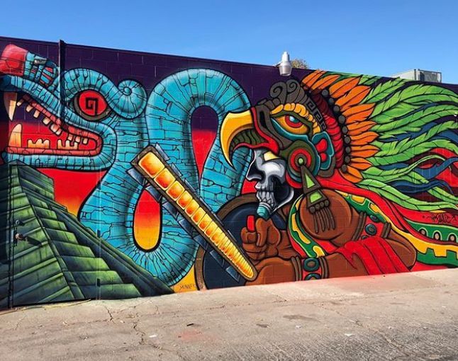 a large colorful mural painted on the side of a building with a dragon and snake