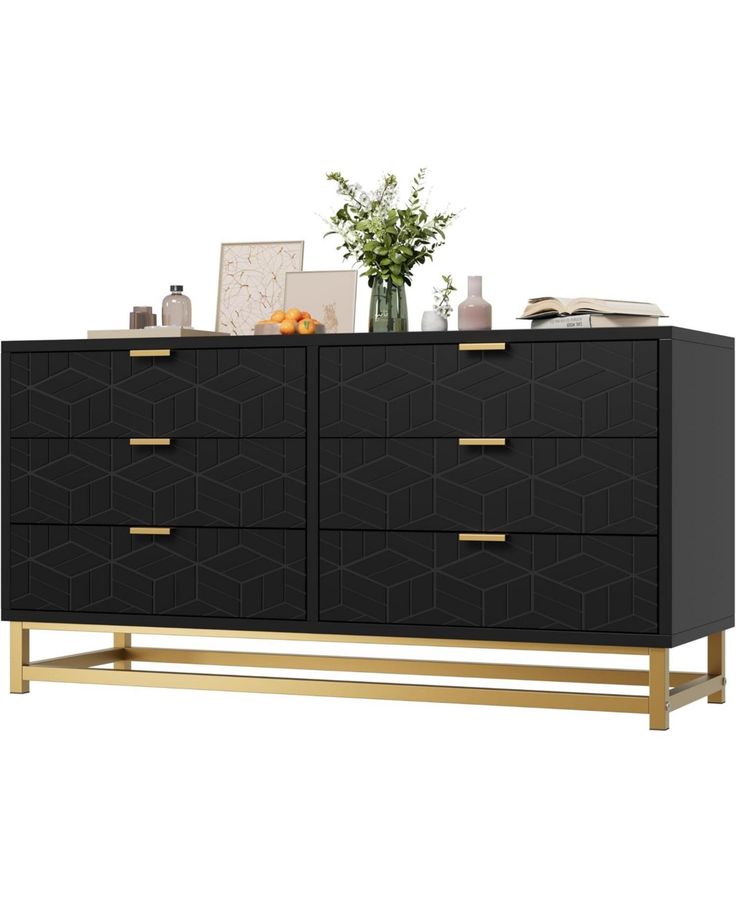 a black dresser with gold handles and drawers on the top, next to a vase filled with flowers