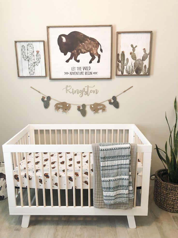 a baby crib in the corner of a room with two pictures on the wall