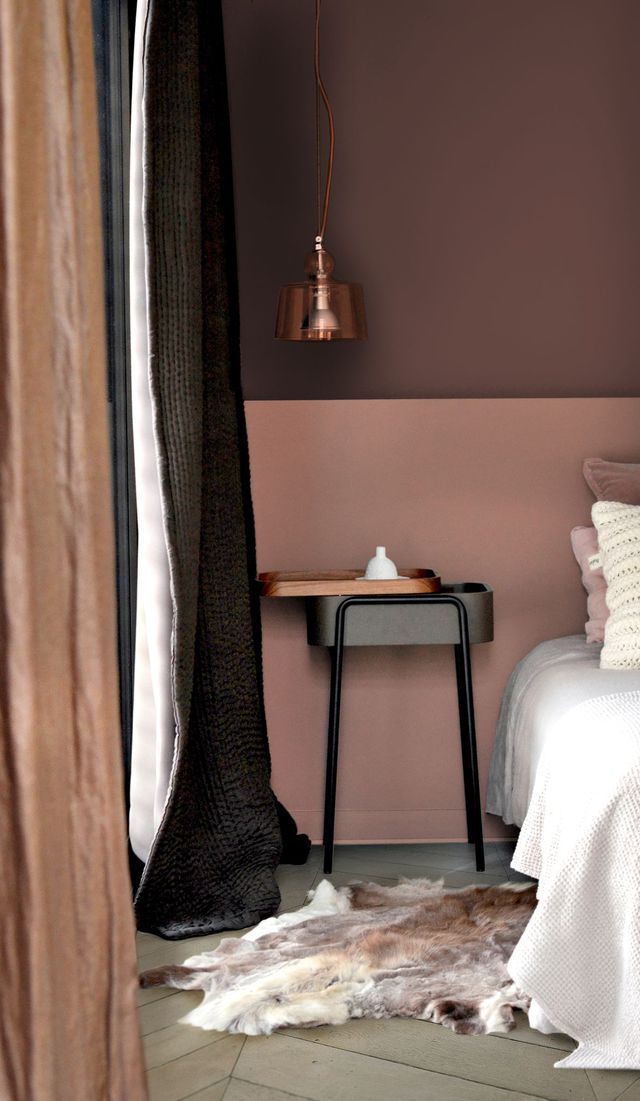 a bedroom with pink walls and a white bed in front of a brown curtained window