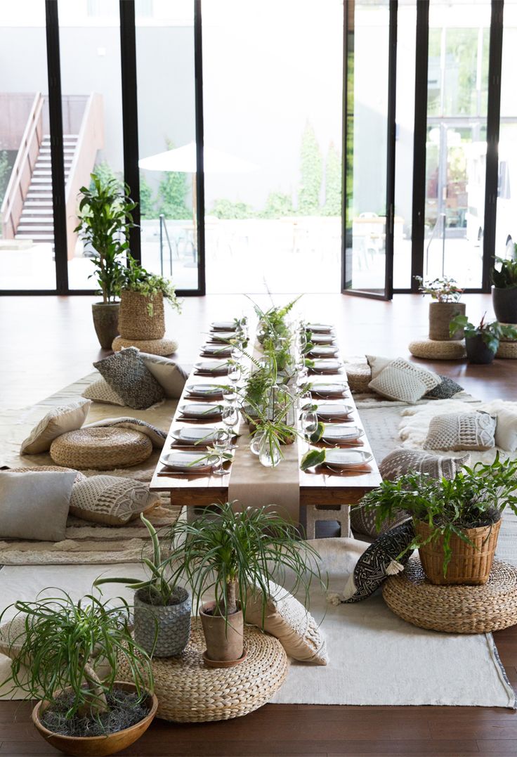 a long table is set with plants and place settings