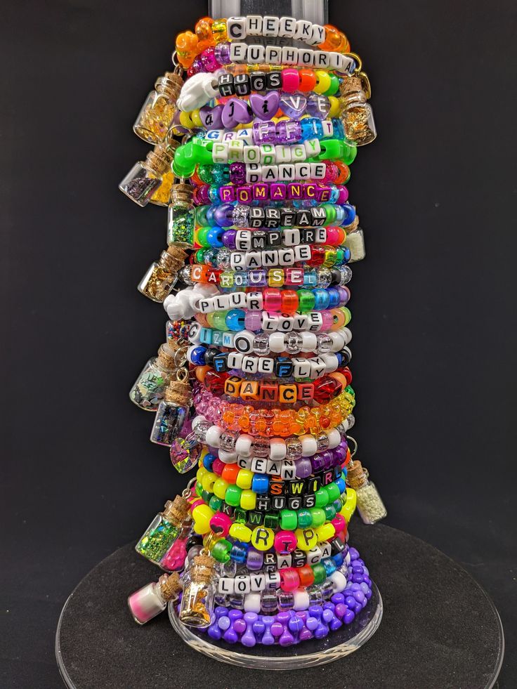 a stack of bracelets that are on top of a black surface with the word love spelled in white letters