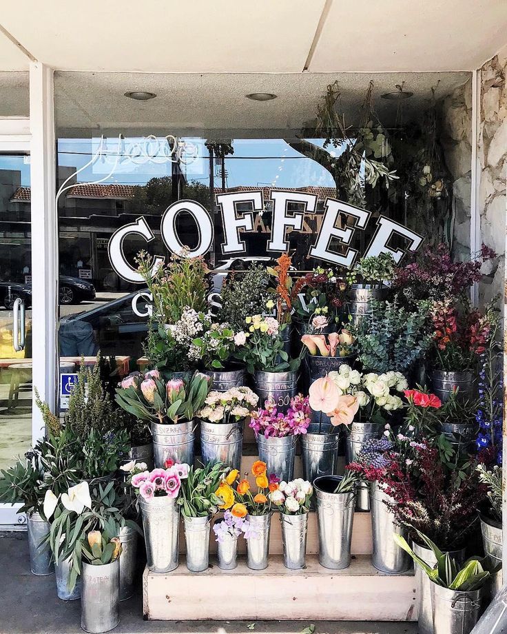 a flower shop with flowers and plants in front of the store's sign that says coffee