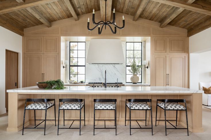 a kitchen with an island and four stools in front of the countertop area