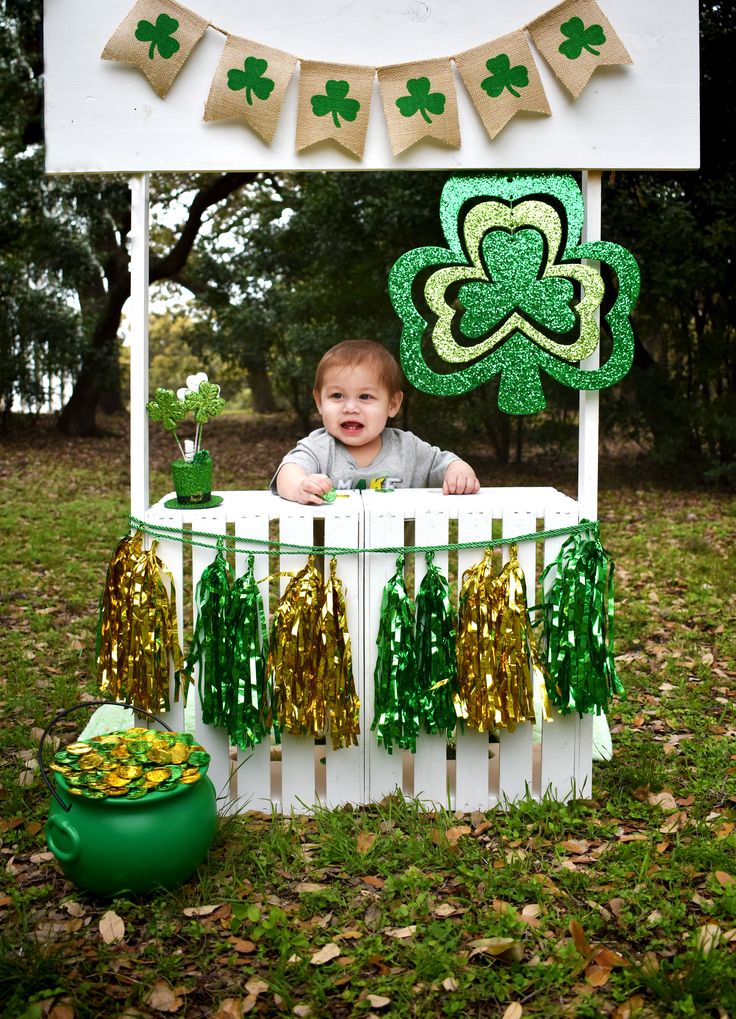 a little boy sitting in a booth at a st patrick's day party