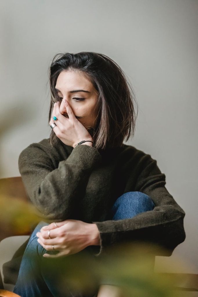 a woman sitting in a chair with her hand on her face