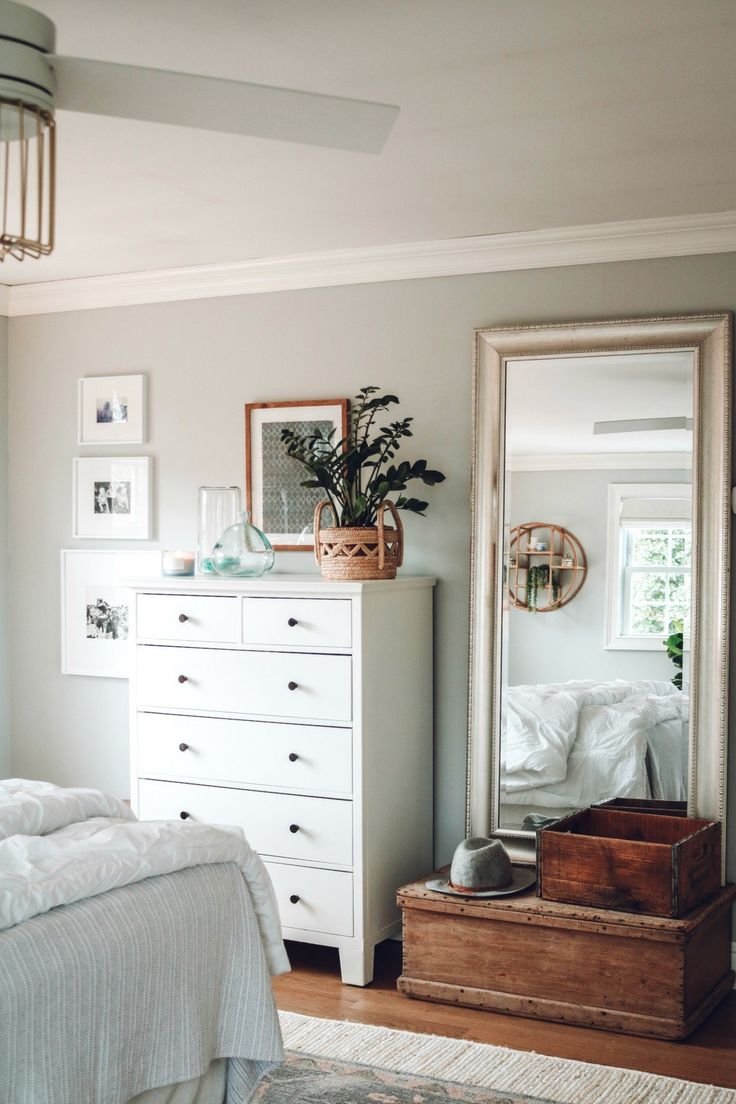 a white dresser sitting next to a bed in a bedroom