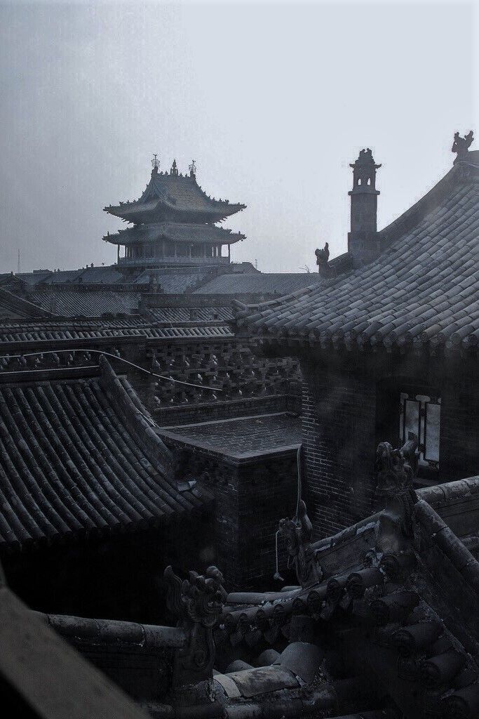 the roofs of an old chinese building are covered in black and white tiles, with pagodas on either side