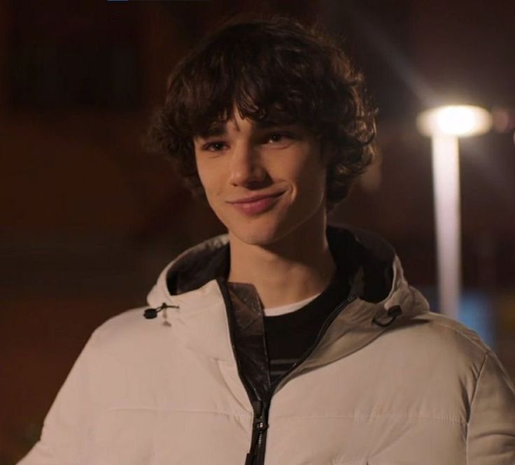 a young man standing in front of a street light wearing a white jacket and black hoodie