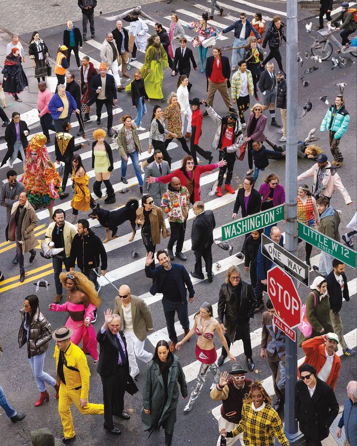 a crowd of people walking across a street next to a stop sign and crosswalk