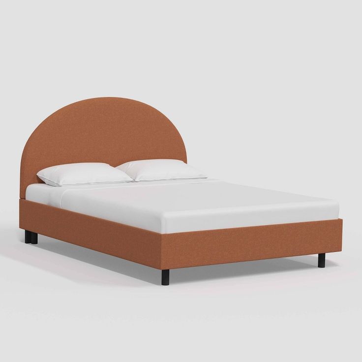 a bed with an orange headboard and white pillows on it's sides, in front of a gray background