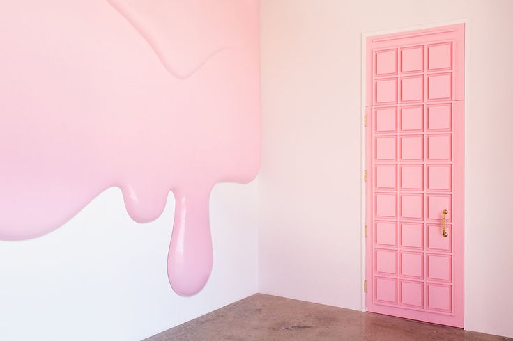 a pink door is in the corner of a room with a painting on the wall