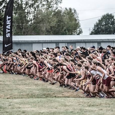 a large group of people are running in a race line with one person on the side