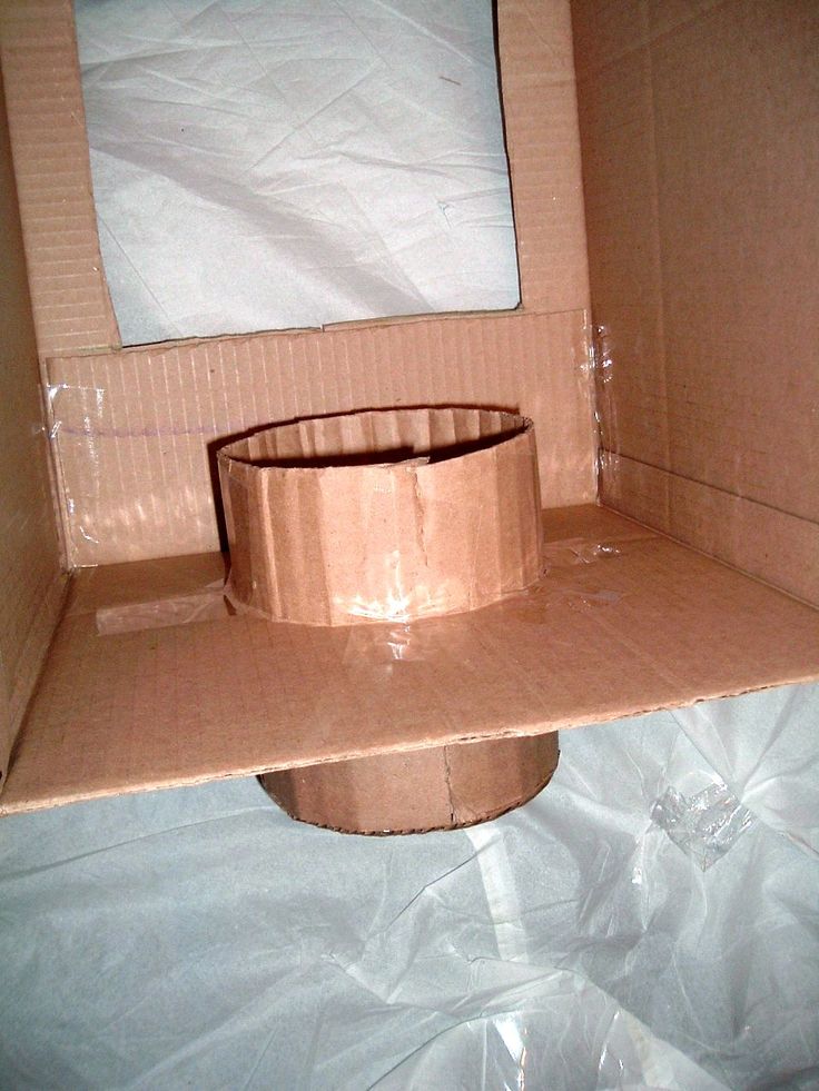 an open cardboard box on top of a white sheeted surface with a round object in the middle