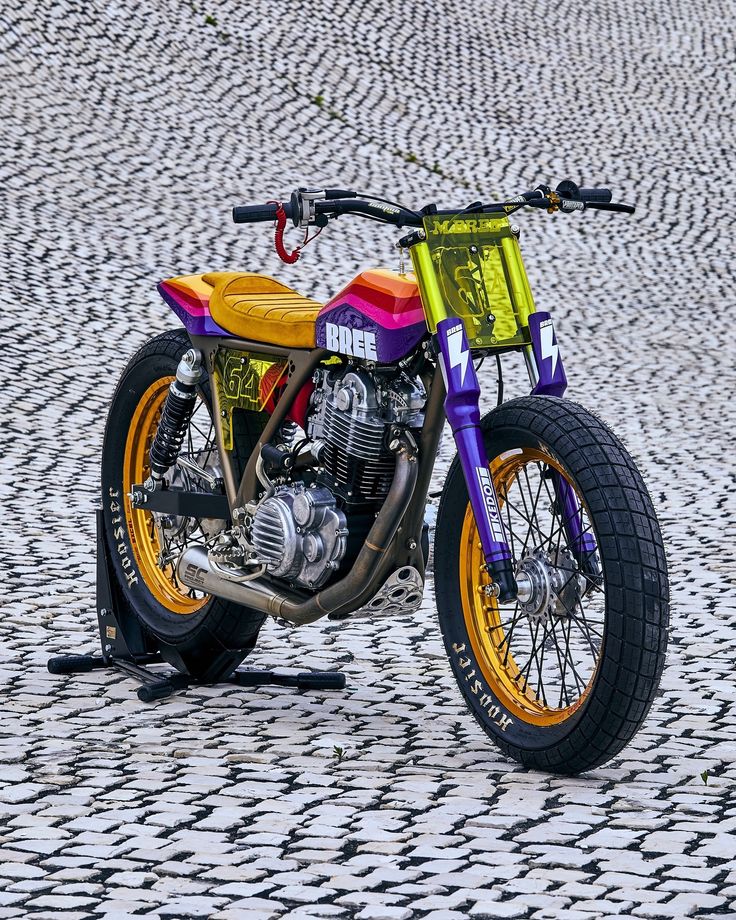 a colorful motorcycle parked on top of a cobblestone road