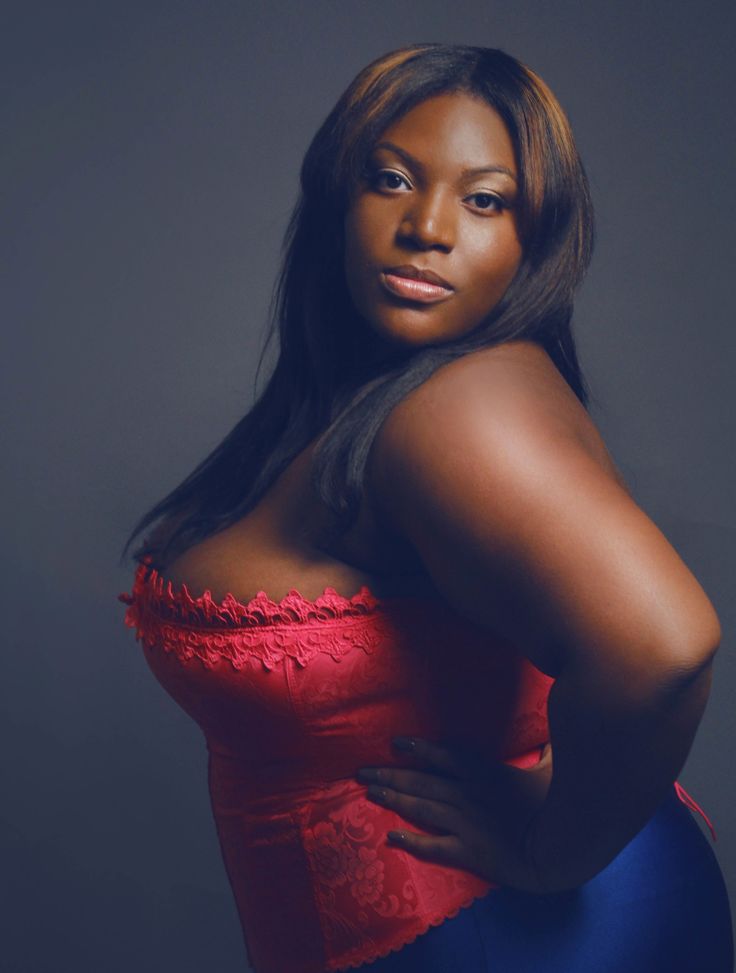 a woman in a red top and blue skirt posing for the camera with her hands on her hips