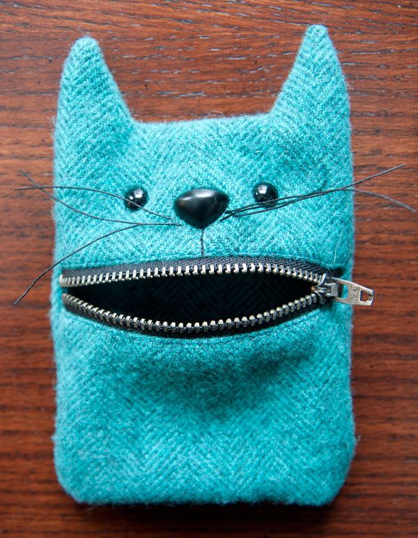 a cat purse with zippers on it sitting on a wooden table next to a pair of scissors