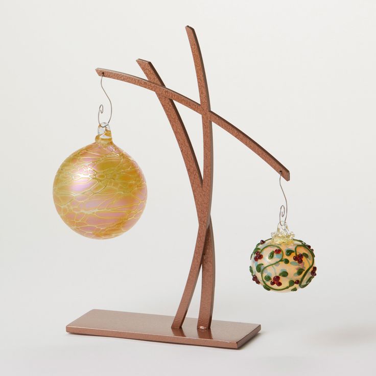 an ornament and christmas ball hanging from a wooden stand on a white background