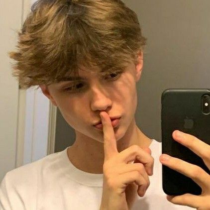 a young man taking a selfie in front of a mirror with his finger to his lips