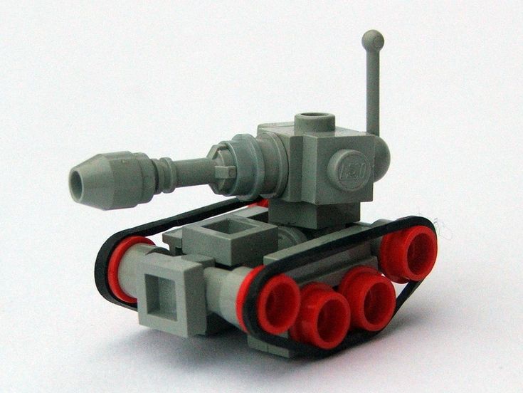 a toy tank with red and black pipes on it's sides, sitting on a white surface